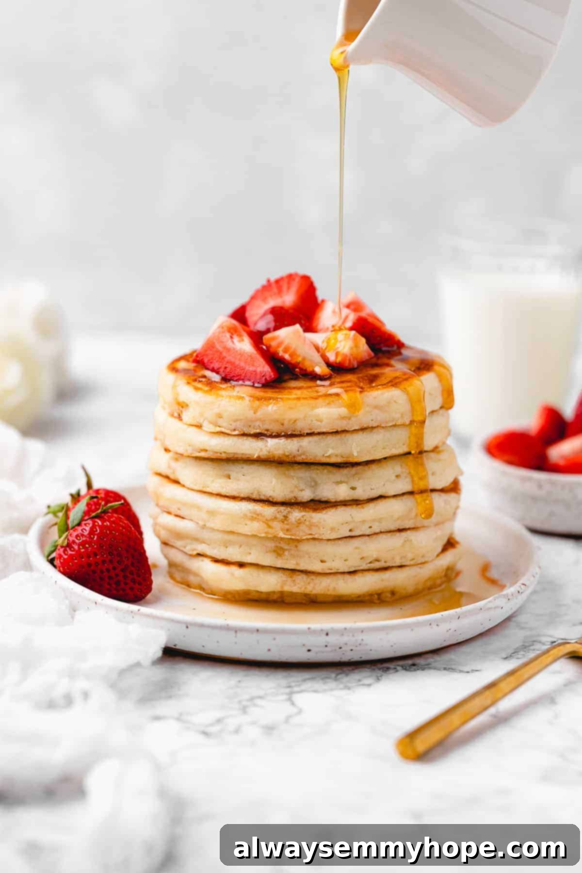 Pancakes topped with strawberry and maple syrup.