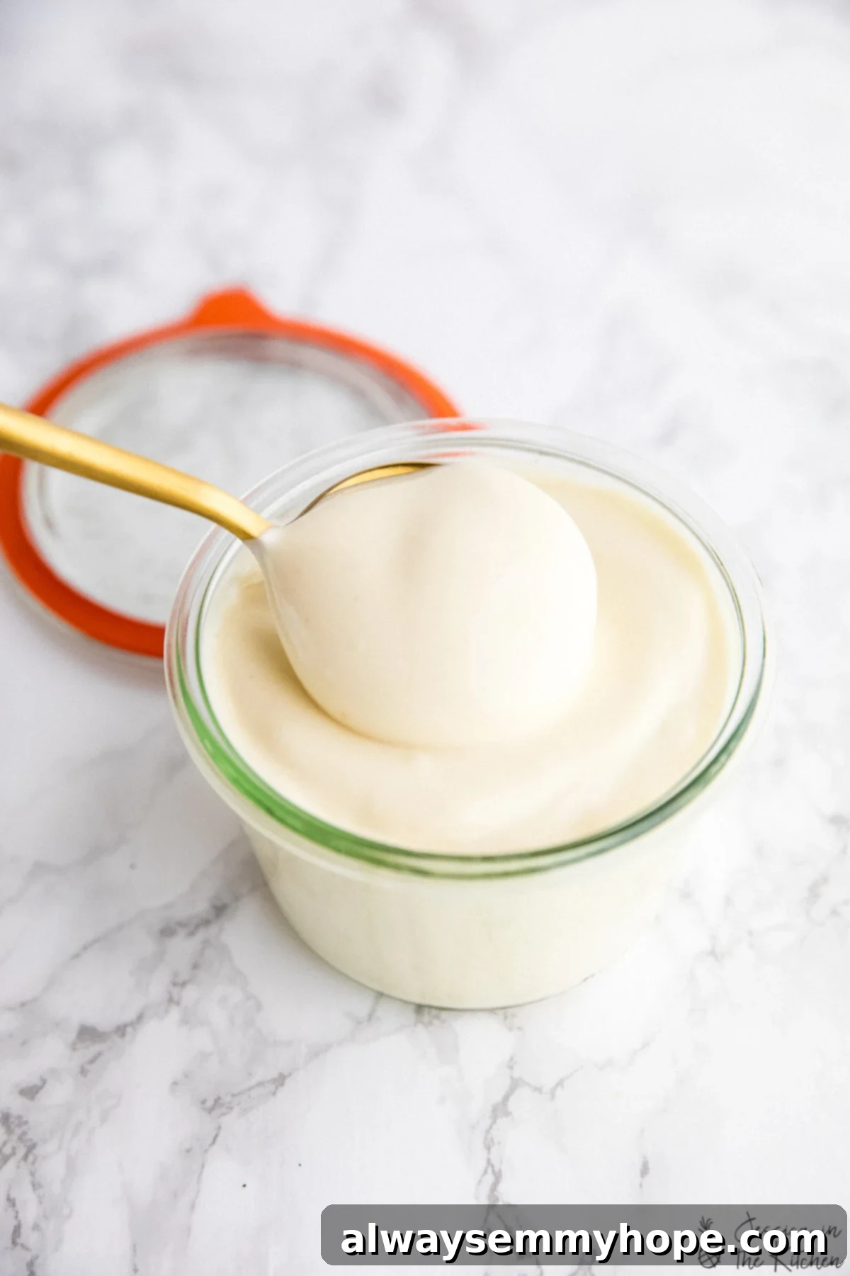 Vegan mayo being scooped out of a jar.