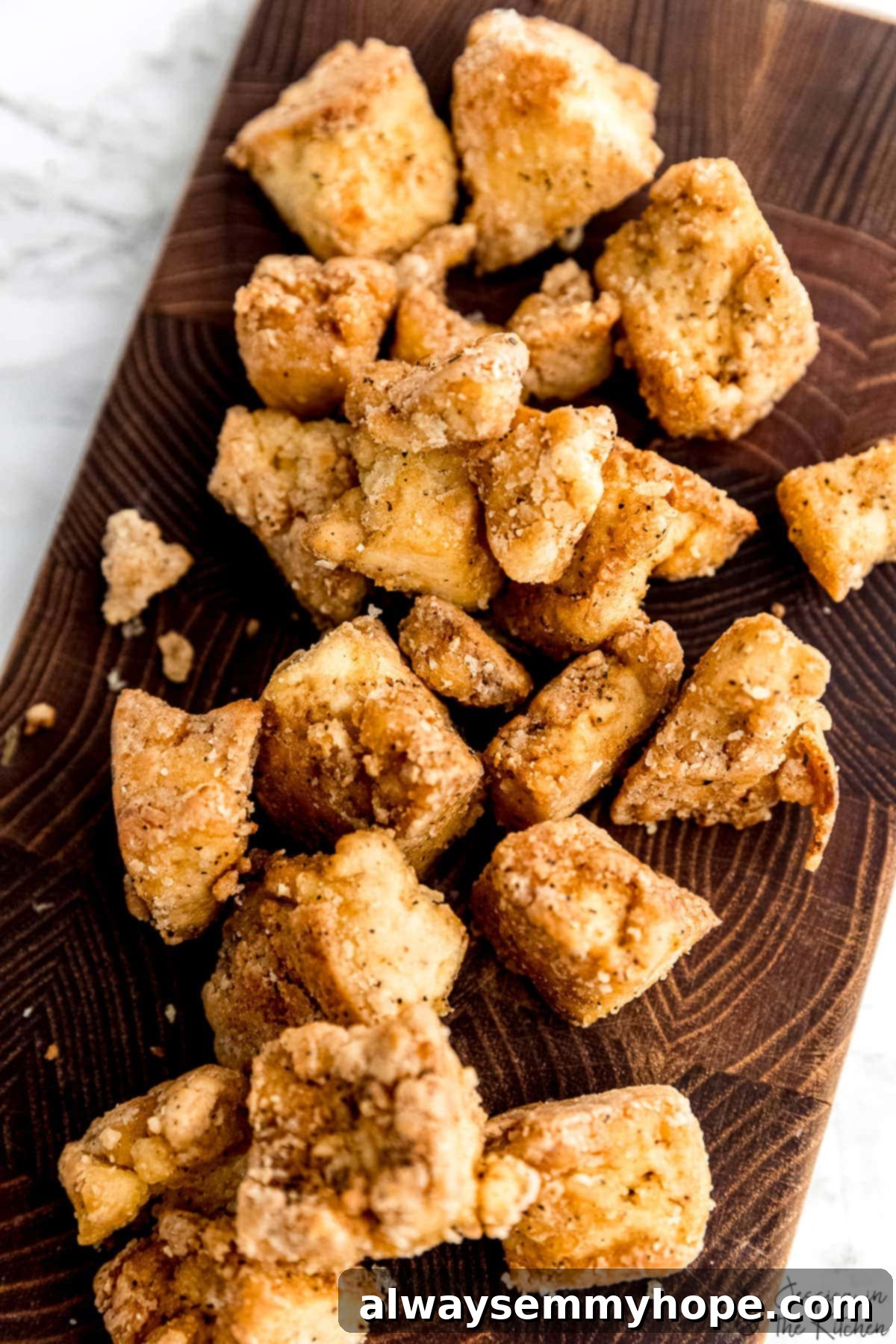 Crispy Vegan Sweet and Sour Tofu 4 Close-up of perfectly crispy tofu pieces cooling on a cutting board after frying.