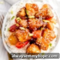 Crispy Vegan Sweet and Sour Tofu 8 Sweet and sour tofu on white rice in a bowl with a fork beside it on a napkin.