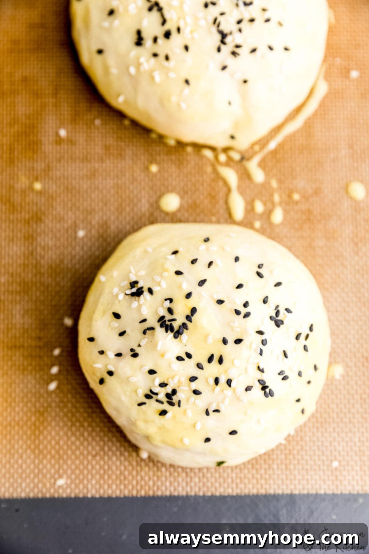 Pillowy Vegan Burger Buns 5 Close-up photo of baked vegan burger buns with sesame seeds, showing golden brown crust.