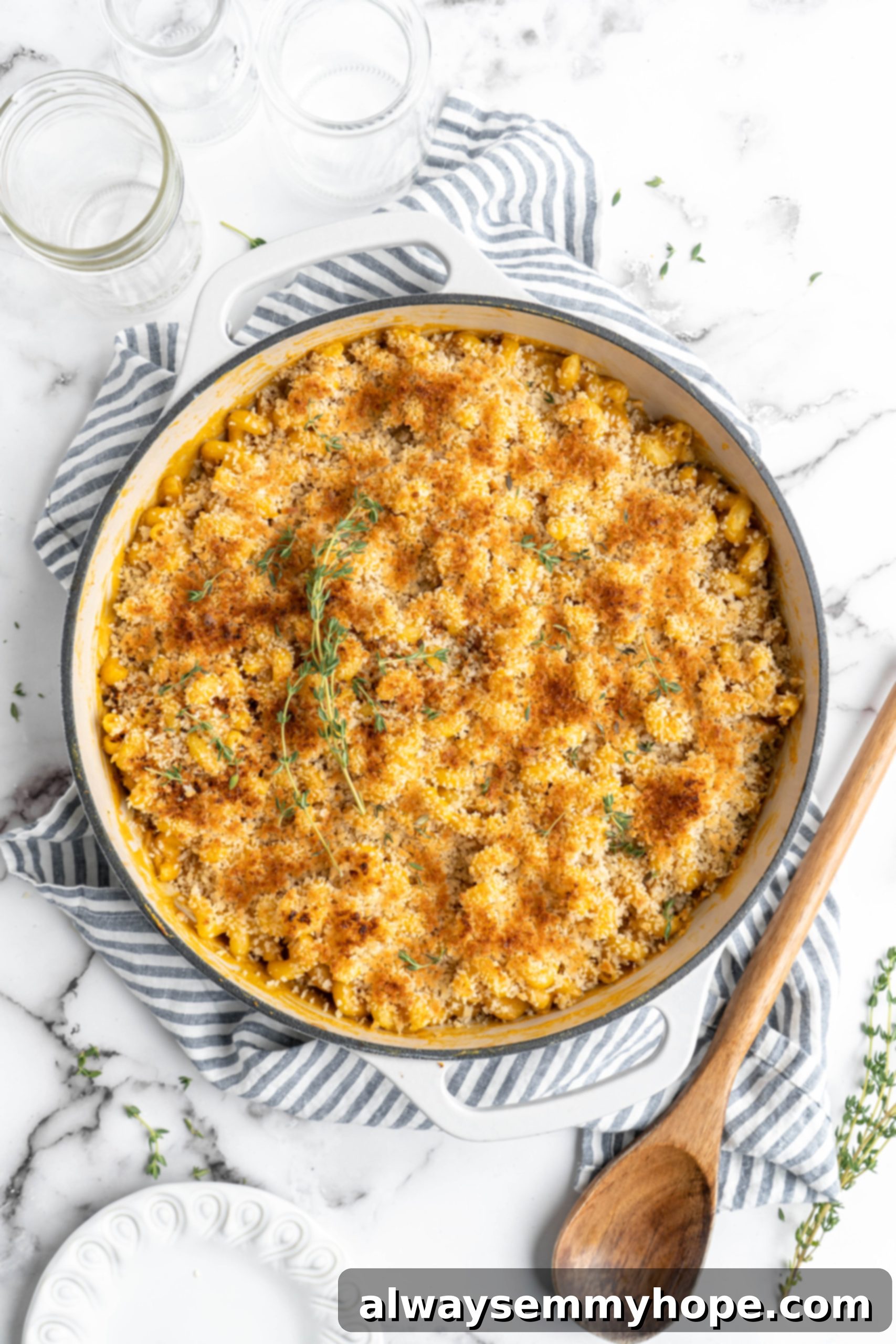 Beautifully baked vegan mac and cheese in a cast iron pan, golden brown and garnished with fresh thyme sprigs, ready to be served.