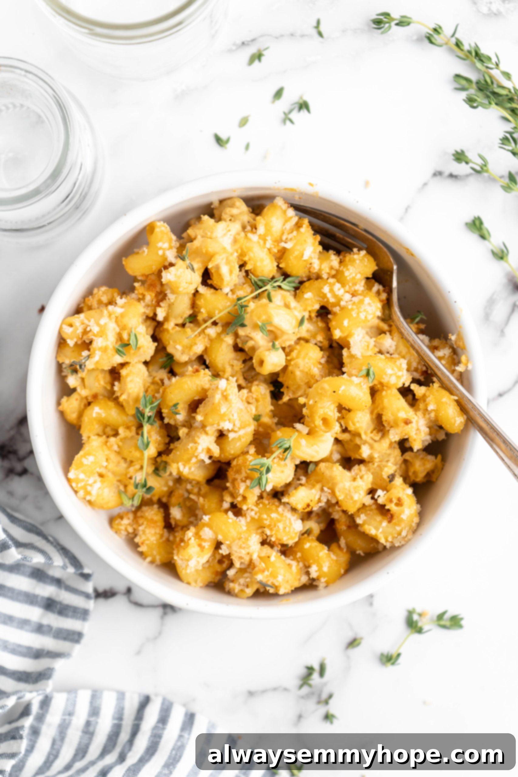 A serving of baked vegan mac and cheese in a white bowl, showing its creamy texture and crispy golden topping, ready to be enjoyed.