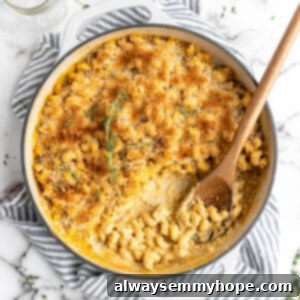 Baked vegan mac and cheese in skillet with wooden spoon, with crispy breadcrumb topping.