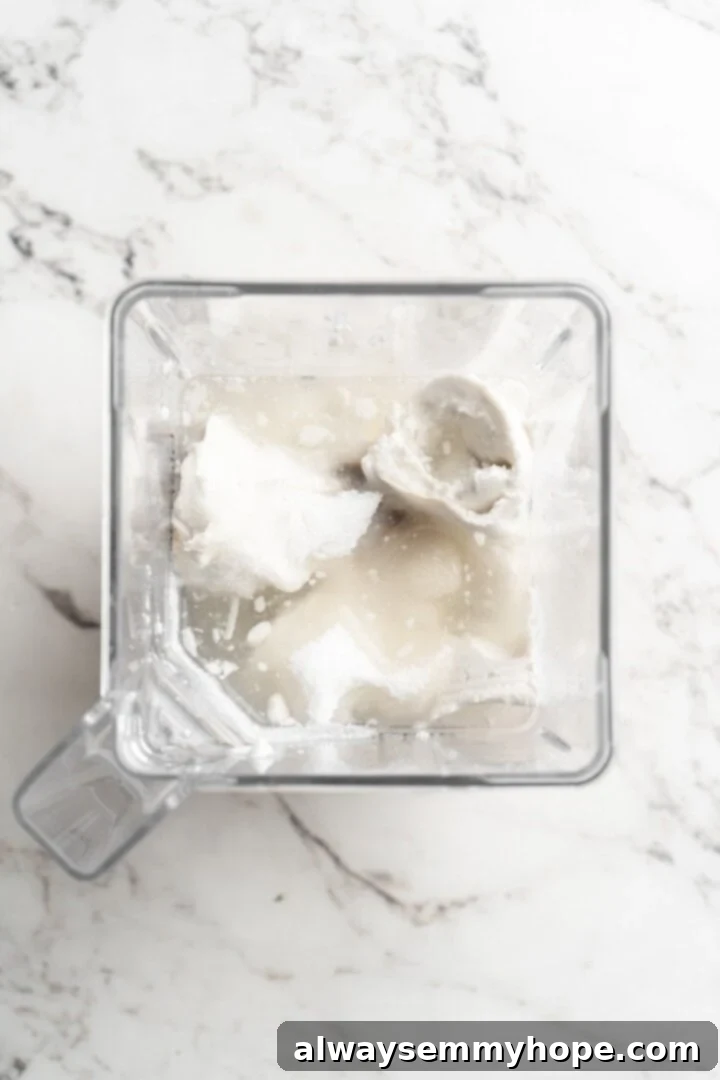 Cover this homemade vegan ice cream very tightly to prevent ice particles from forming. It will keep fresh in the freezer for up to 2 weeks. Overhead view of soaked cashews and full-fat coconut milk being added to a blender for vegan ice cream