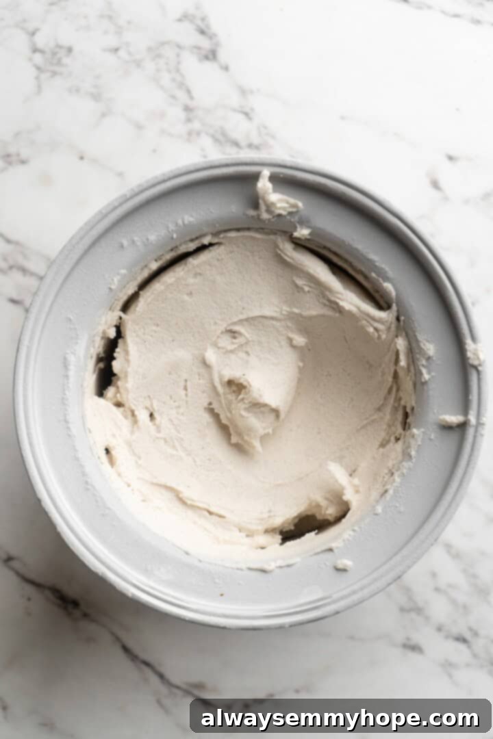 Cover this homemade vegan ice cream very tightly to prevent ice particles from forming. It will keep fresh in the freezer for up to 2 weeks. Overhead view of the vegan ice cream mixture churning in an ice cream maker, gradually thickening