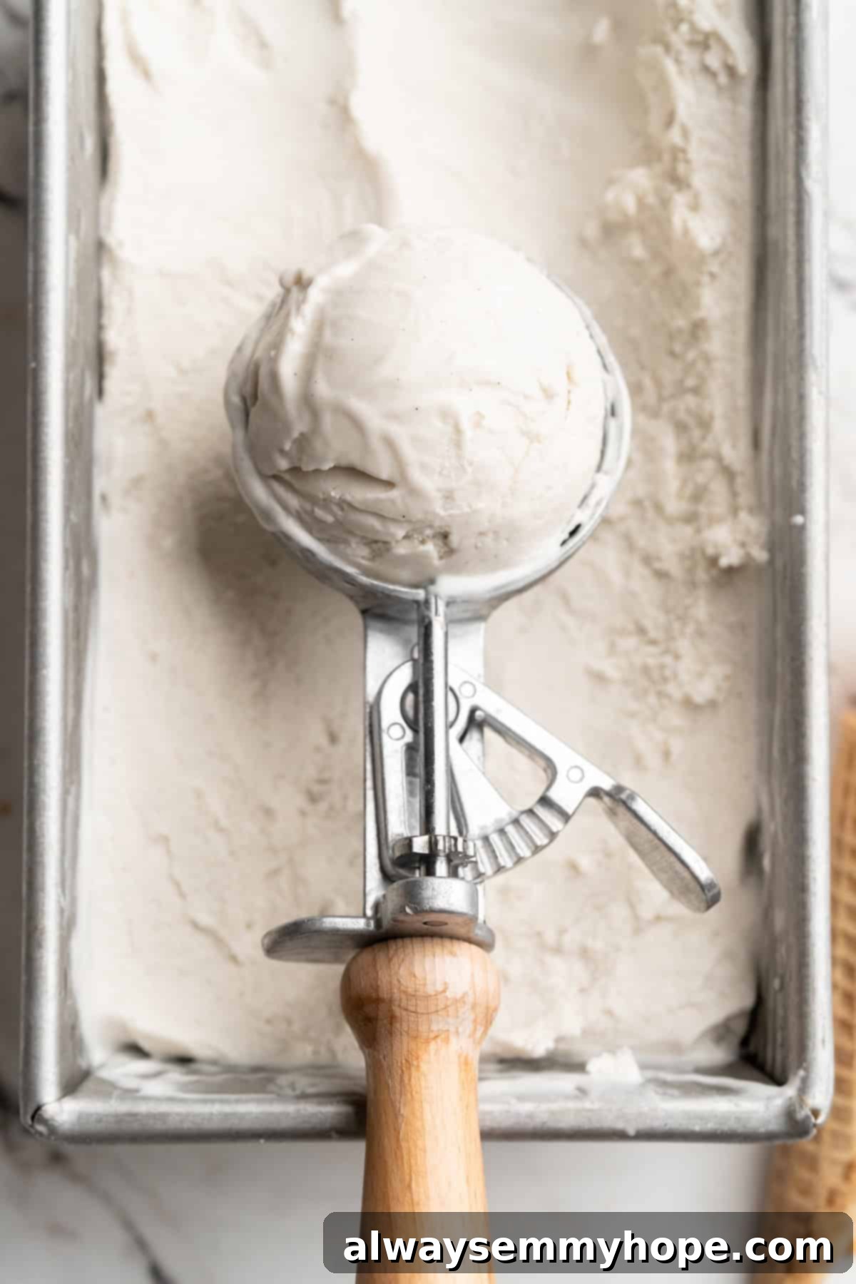 Cover this homemade vegan ice cream very tightly to prevent ice particles from forming. It will keep fresh in the freezer for up to 2 weeks. Overhead view of a scoop of vanilla vegan ice cream resting in a scooped-out portion of a loaf pan