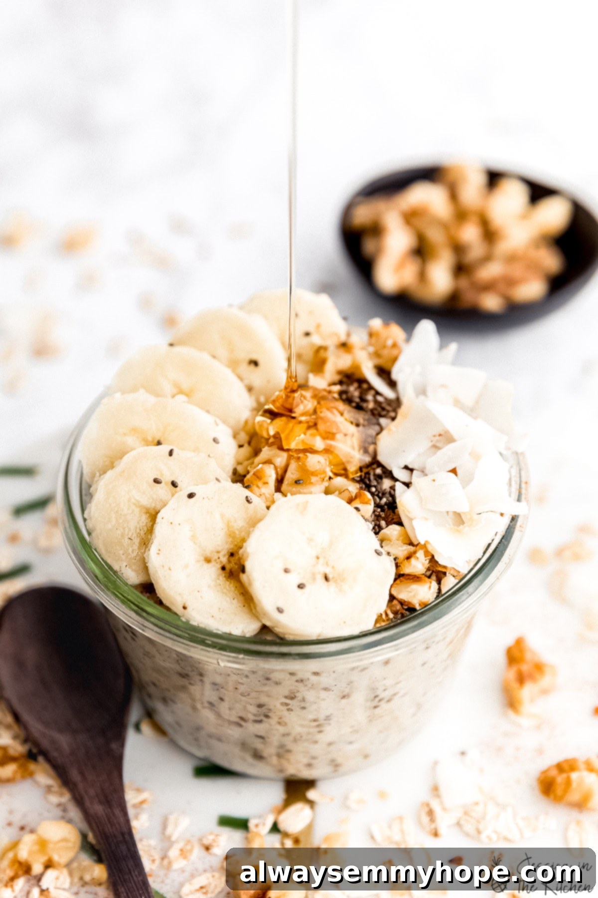 These banana bread overnight oats taste like dessert for breakfast! This easy recipe is filling, nourishing, and excellent for meal prep. Maple syrup being drizzled into a jar of overnight oats.