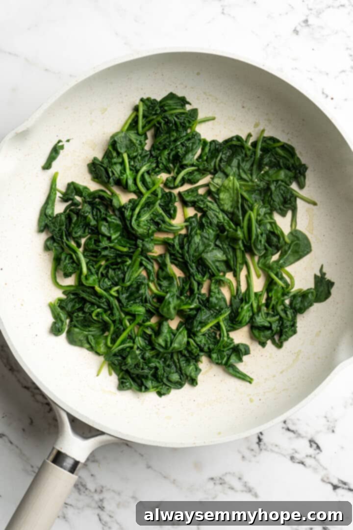 Wilted spinach in the skillet, ready for the artichokes. Wilted spinach leaves in a skillet, having released their moisture, ready for the next step of the dip preparation.