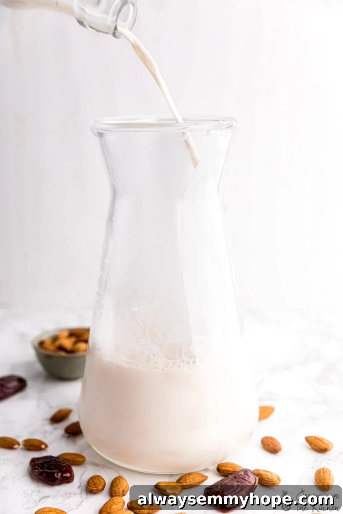 Homemade Almond Milk: The Ultimate Guide to Creamy, Easy, and Customizable Plant-Based Milk Almond milk being poured into a jar with raw almonds and dates surrounding it.