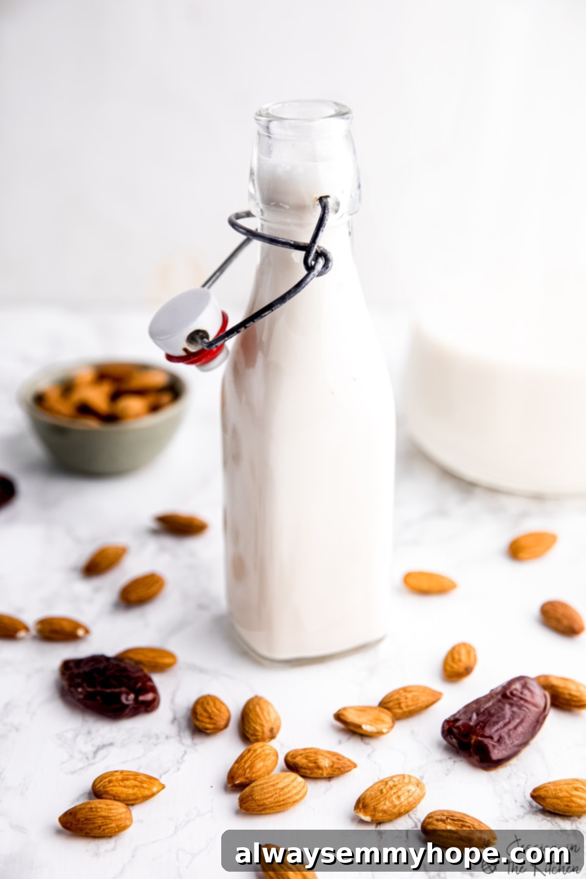 Homemade almond milk in a glass milk jar, surrounded by raw almonds and fresh dates, emphasizing its natural ingredients.