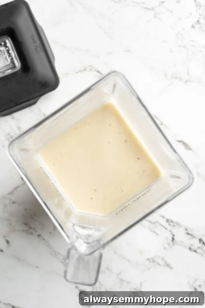 Overhead shot of the creamy, blended vegan butter mixture swirling in a high-speed blender before being poured into a mold.