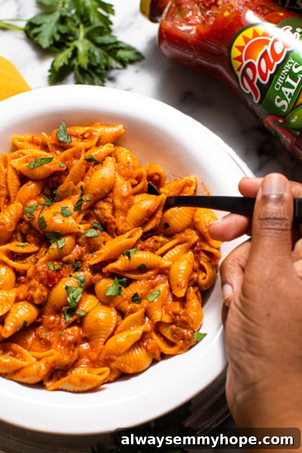 Close-up of a spoon digging into a bowl of cheesy vegan taco pasta