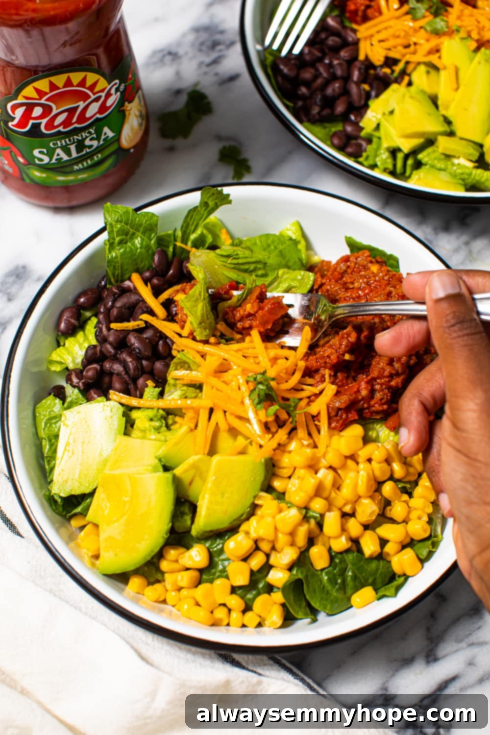 Close-up of a fork digging into a bowl of vibrant vegan taco salad