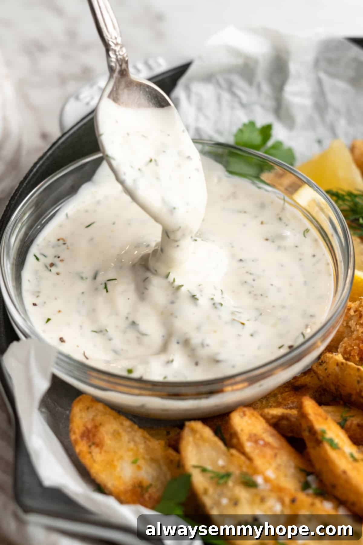 A spoon skillfully drizzles rich, creamy vegan tartar sauce back into a rustic ceramic bowl, highlighting its thick and luscious texture, ready to accompany any plant-based dish.