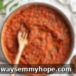 Overhead view of bubbling arrabbiata sauce in a rustic skillet, with a wooden spoon stirring, garnished with fresh herbs.