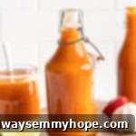 An assortment of bottles and a jar filled with vibrant homemade Scotch bonnet pepper hot sauce, showcasing its rich colour.