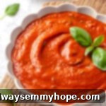 A rustic bowl filled with homemade pomodoro sauce, showcasing its rich red colour and fresh basil garnish.