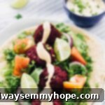 Vibrant beet falafels arranged on warm pita bread, generously topped with fresh salad and a delectable harissa tahini dressing.