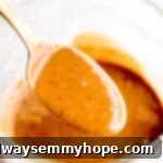 Golden spoon gracefully hovering over a jar filled with rich, creamy Thai peanut sauce, ready to be served.