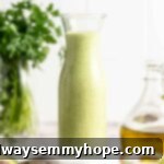 Tall glass jar filled with luscious, vibrant green avocado dressing, perfectly creamy and ready to serve.