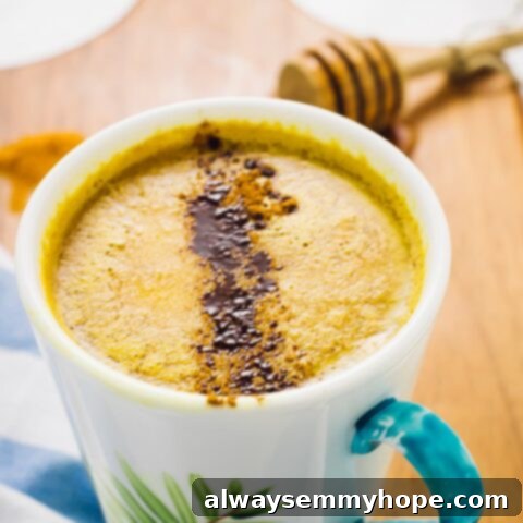 A golden Pumpkin Spice Golden Milk with spices sprinkled on top.