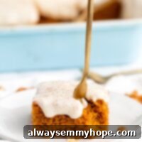 Spiced Vegan Pumpkin Sheet Cake 2 A fork being stuck into a pumpkin cake on a plate with a bite missing in front of a blue container filled with slices of cake.