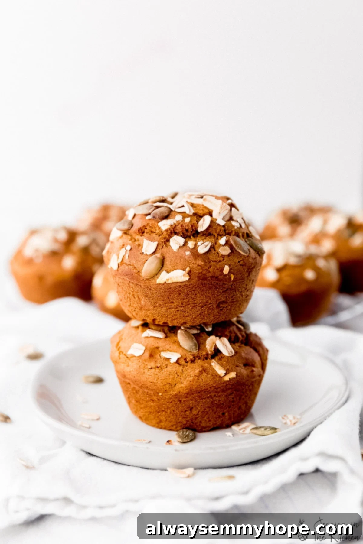 Side shot of two stacked vegan pumpkin muffins on a plate.
