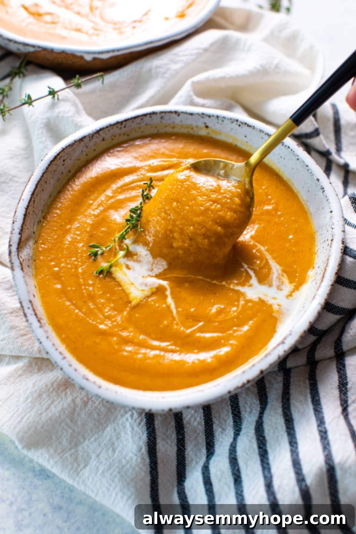Spoon pulling some vegan pumpkin soup out of a bowl.