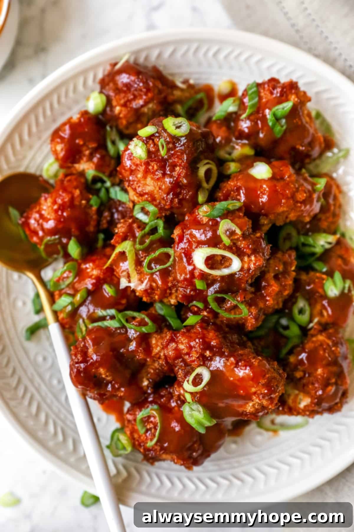 BBQ cauliflower wings are perfect for game day appetizers or make them your main dish on a weeknight. So easy and delicious! Bbq cauliflower wings on a plate with a spoon beside it.