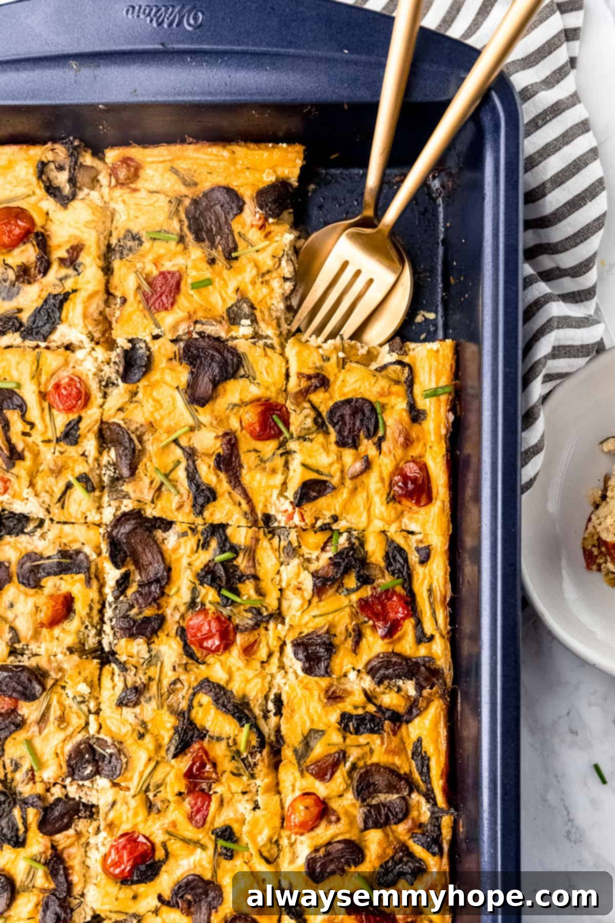 Vegan frittata in a baking sheet with fork and spoon in it.