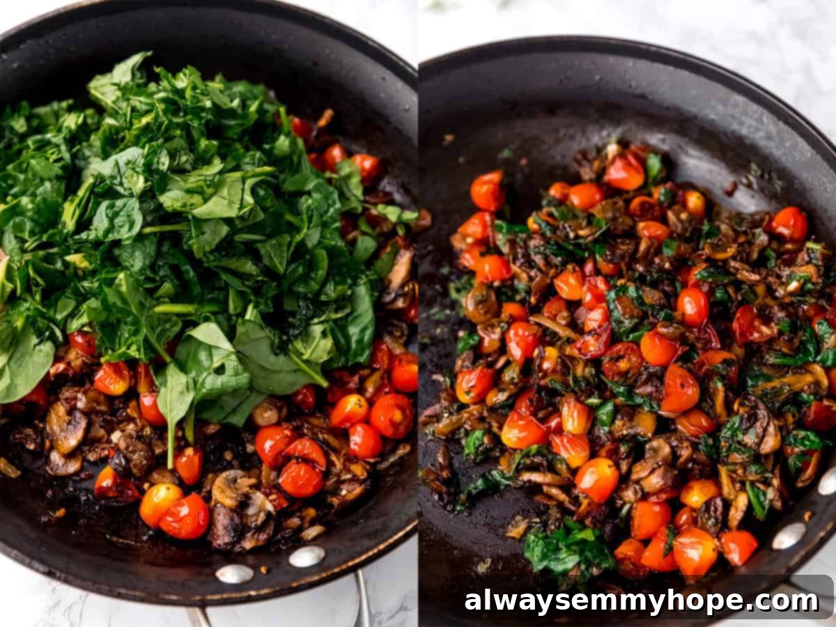 Top down shot of greens cooking in a pan with tomatoes and mushrooms.