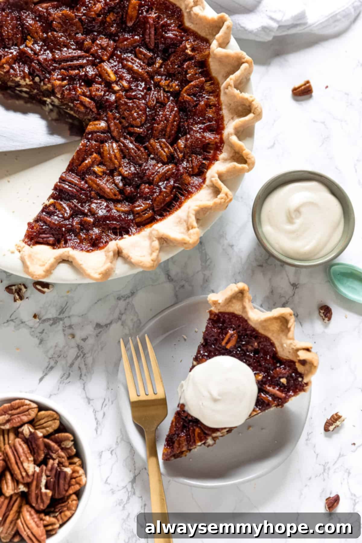 Overhead view of a slice of vegan pecan pie topped with whipped cream on a plate with a fork, next to a small bowl of whipped cream and the rest of the pie in a pie plate.