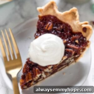 Close up of a slice of vegan pecan pie on a plate with a dollop of whipped cream on top, next to a fork.