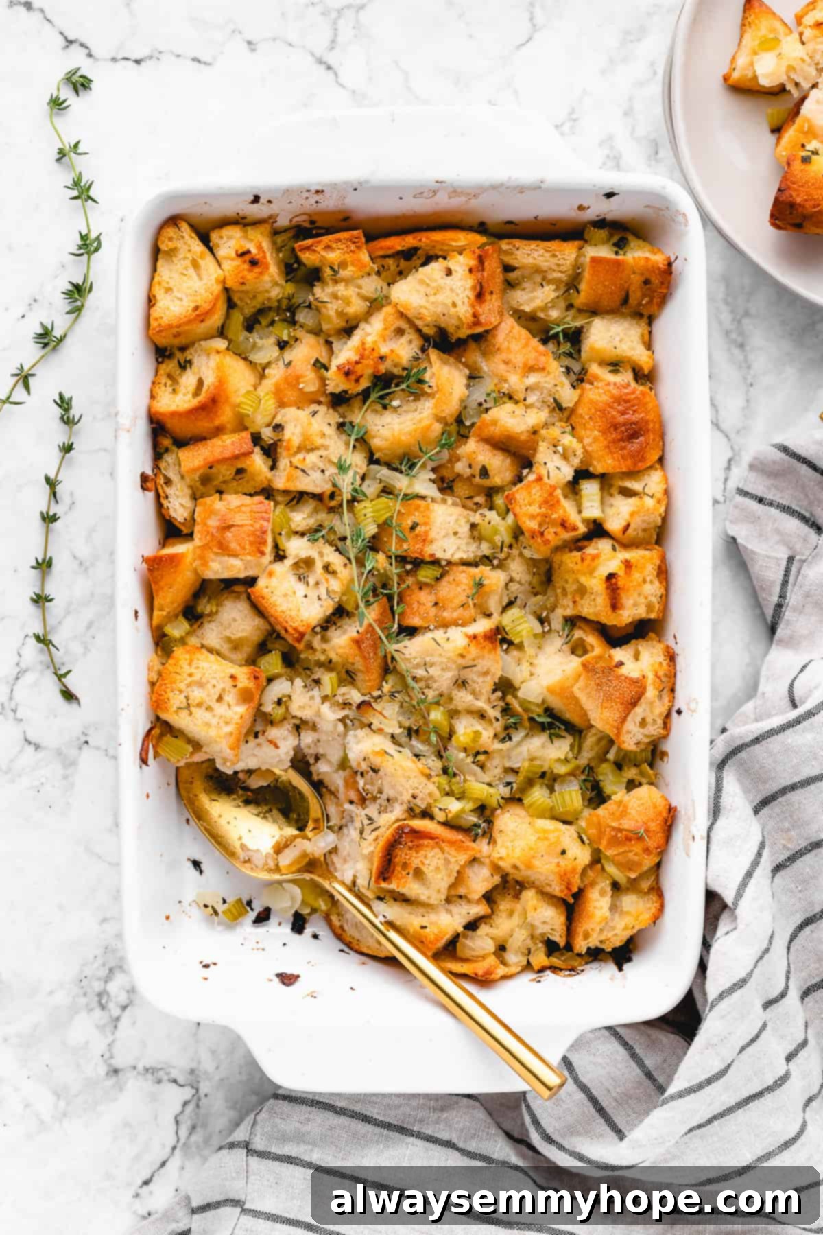 A golden-brown vegan stuffing in a casserole dish, with a serving spoon and a portion scooped out, showcasing its delicious texture.