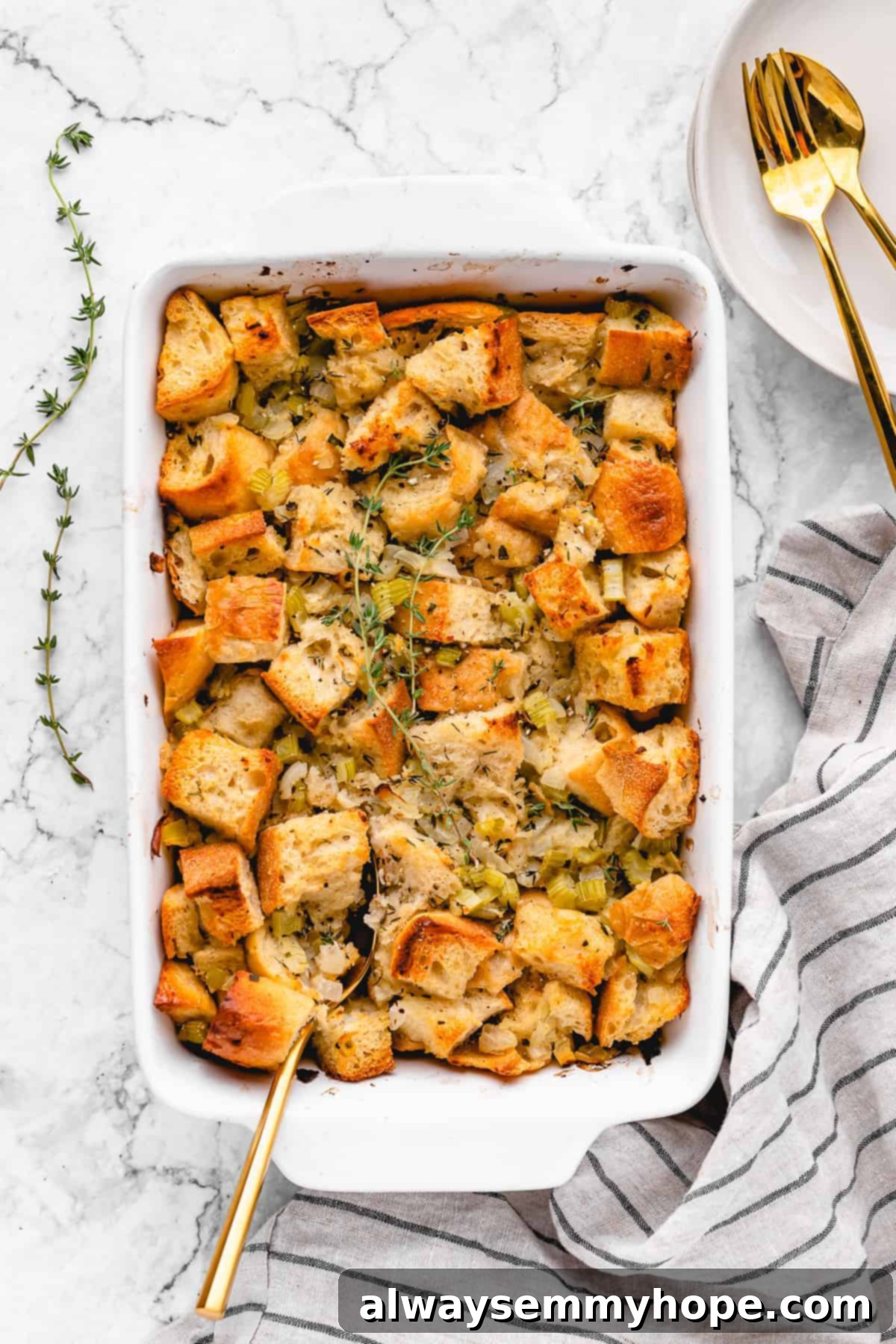 A close-up shot of vegan stuffing in a casserole dish, with a spoon nestled into its golden-brown, herby surface, inviting a taste.