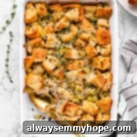 A golden-brown vegan stuffing in a casserole dish, with a serving spoon and a portion scooped out, showcasing its delicious texture.
