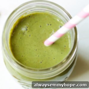 Overhead view of strawberry kale smoothie in mason jar with pink and white striped straw