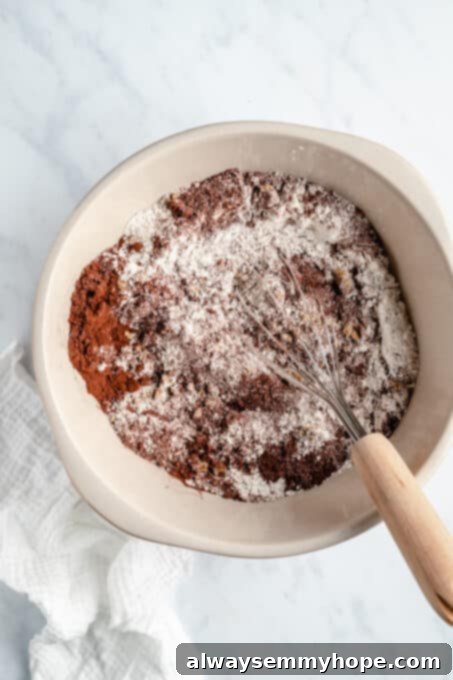 Close-up of a large bowl filled with dry ingredients for chocolate cake, including flour, cocoa powder, and sugar.