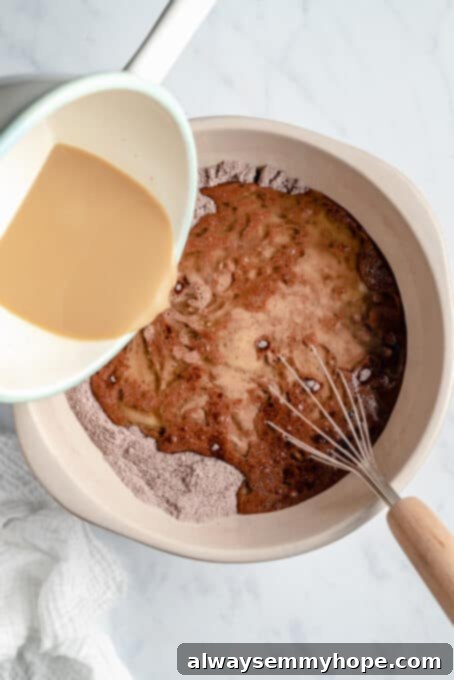 Warm milk and instant coffee being added to the vegan chocolate cake batter.