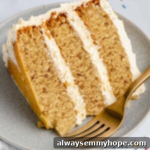 Classic Vegan Vanilla Cake with Buttercream Frosting 3 A perfectly sliced piece of vegan vanilla cake on a plate, ready to be served, with a gold fork.