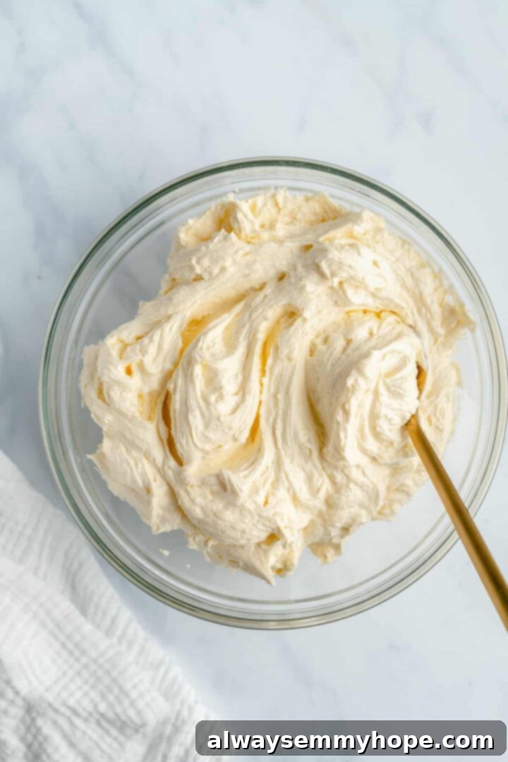 Whip up a batch of our dreamy vegan buttercream frosting to complement your homemade vanilla cake perfectly. A bowl of fluffy, white vegan buttercream frosting, freshly whipped and ready for decorating a cake.