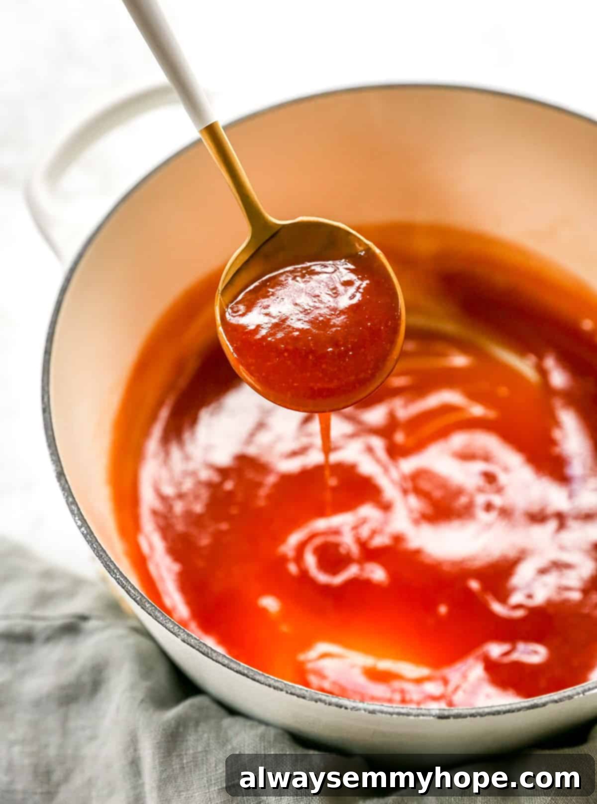 Crispy Sweet and Sour Cauliflower Wings 9 A spoon lifts glossy, rich sweet and sour sauce from a pan, showing its perfect thickened consistency.