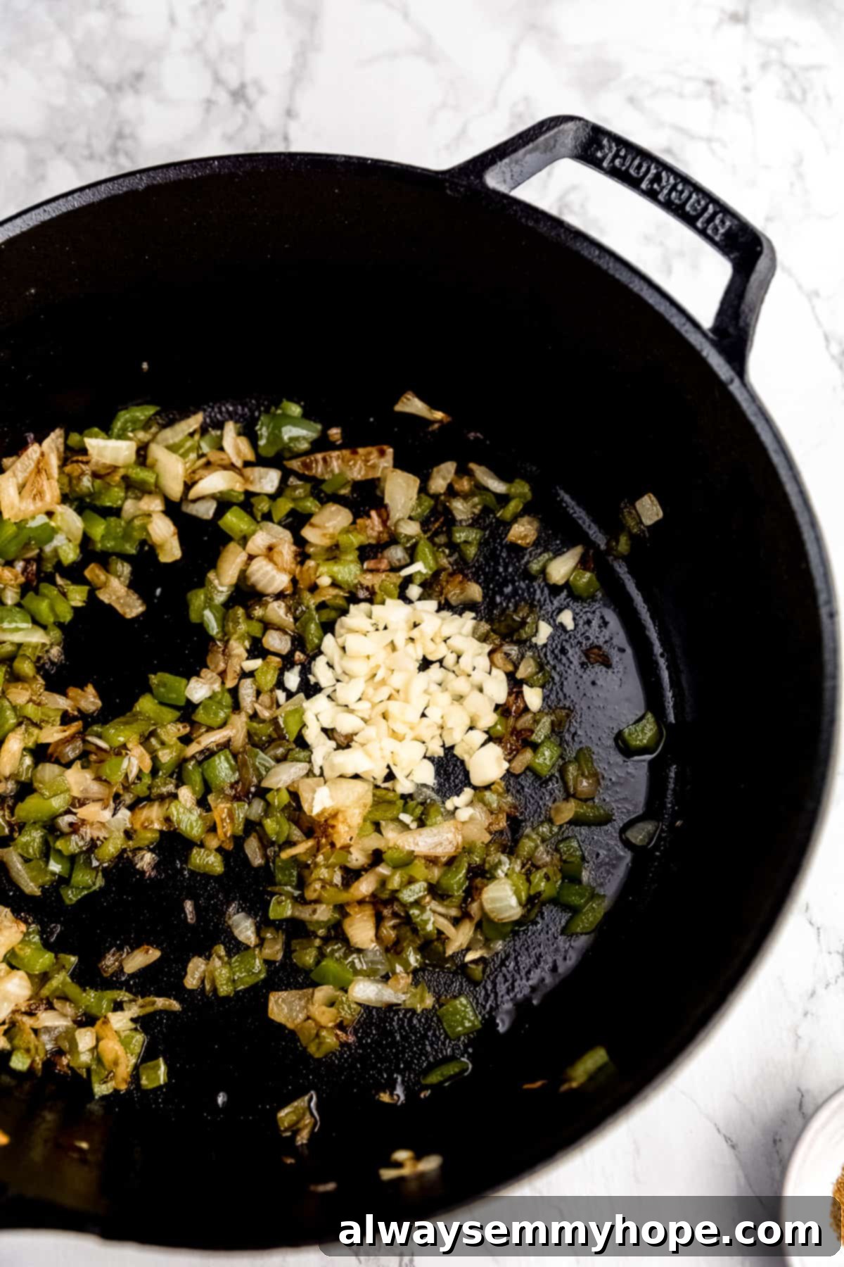 Wholesome Vegan Shakshuka 8 Chopped garlic being added to the sautéed onions and bell peppers in a cast iron skillet, filling the kitchen with an inviting, savory aroma.