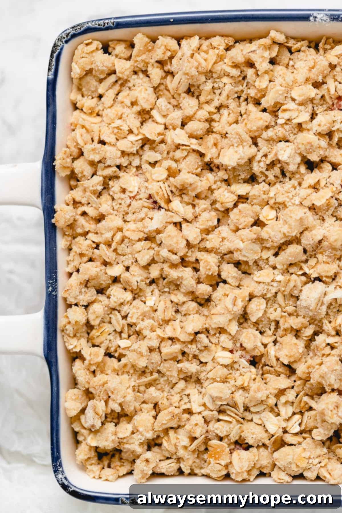 Vegan Strawberry Crisp Ready for Baking Close-up overhead view of unbaked strawberry crisp, showing the even layer of oat topping covering the fruit filling.