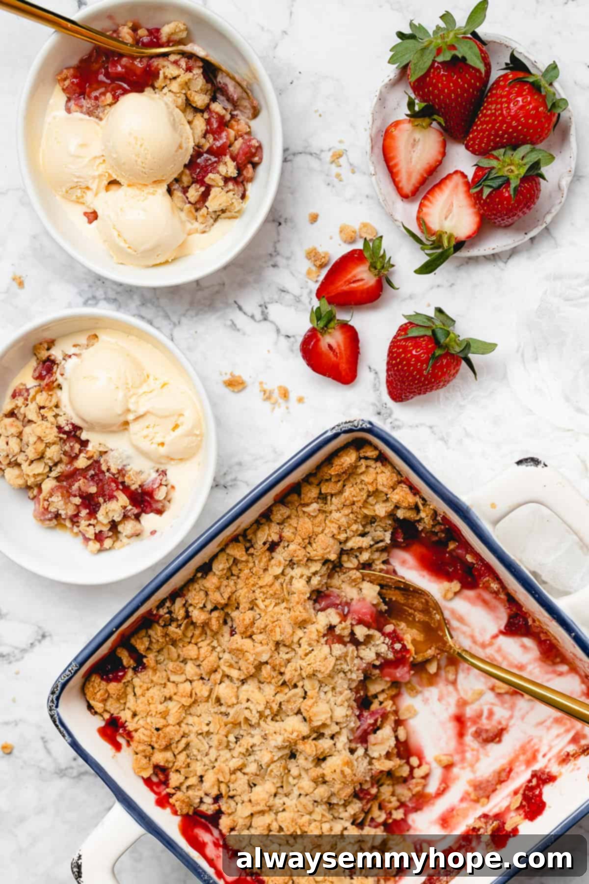 Serving Warm Vegan Strawberry Crisp with Ice Cream Overhead shot of two servings of vegan strawberry crisp topped with ice cream, with the remaining crisp in a baking dish in the background, ready for more servings.