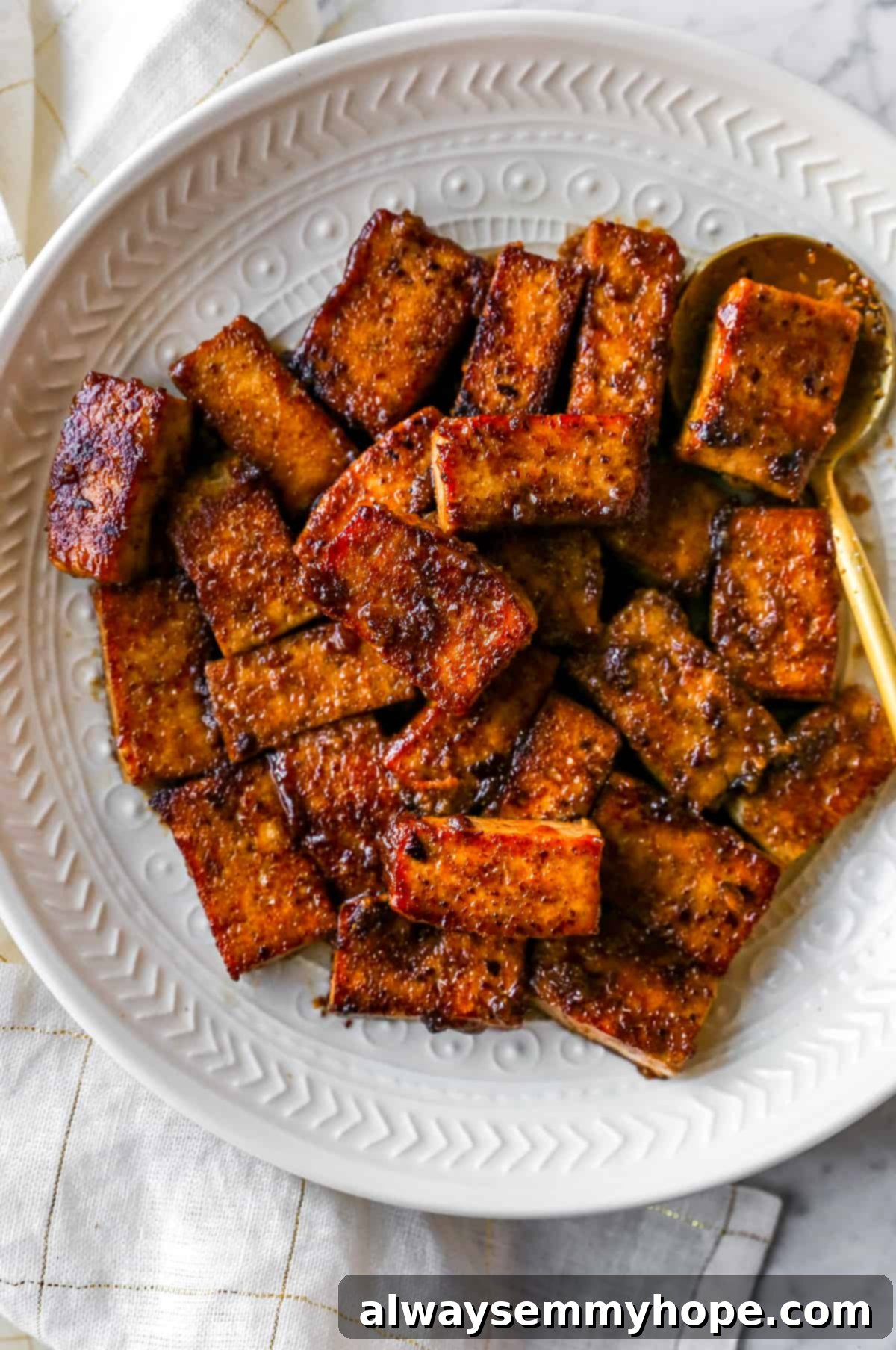 A plate of perfectly cooked and sauced marinated tofu, garnished and ready to be enjoyed.