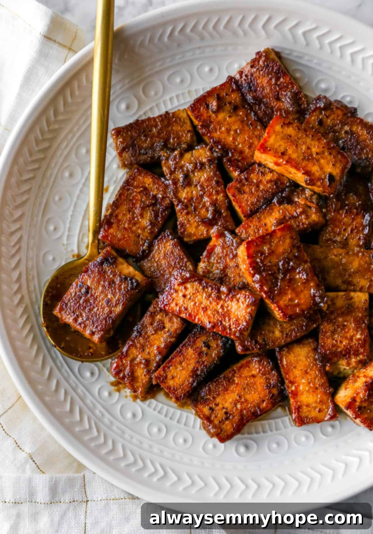 15 Amazing Tofu Recipes 2 marinated and cooked tofu on a plate with a gold spoon holding some tofu