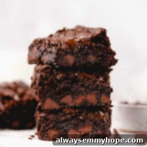 three gluten-free vegan brownies stacked on top of one another with one in the corner and a bowl of chocolate chips