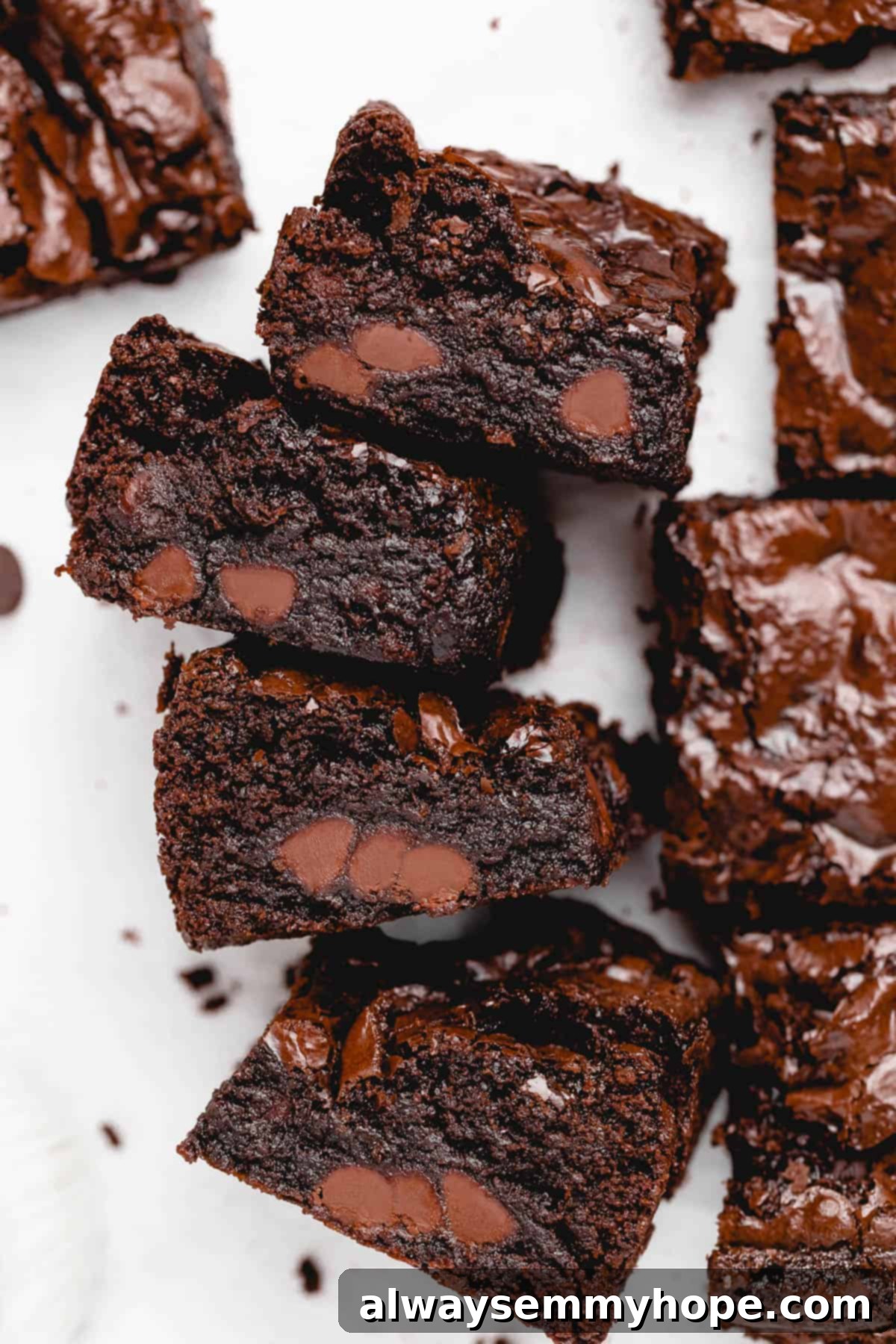 four gluten-free vegan brownies stacked sideways surrounded by other brownies
